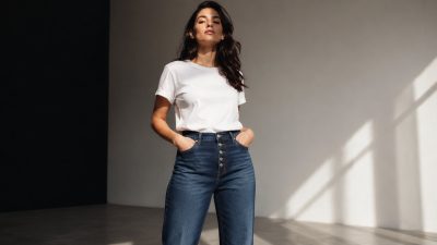 Flat lay of folded indigo jeans with tailor's measuring tape on wooden surface, soft natural light