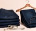 Indigo jeans air-drying on a wooden clothesline in soft natural light, minimalist setting