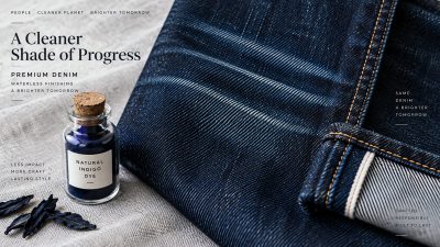 Stack of indigo jeans with a tailor's measuring tape on a rustic wooden table in soft natural light
