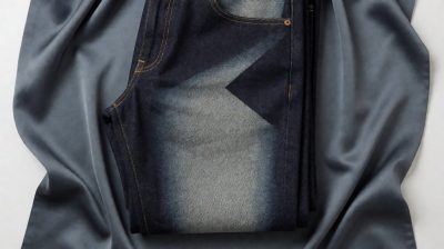 Industrial laser etches fade pattern onto indigo denim in bright clean factory setting