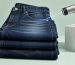 Industrial laser etching a fade pattern onto dark indigo denim in a clean minimalist workshop, soft natural light