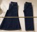Stack of folded indigo jeans beside a pair on a wooden hanger with a tailor tape measure on a light surface